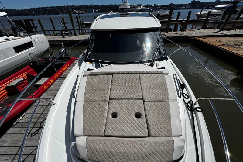  Yacht Photos Pics 2019 Jeanneau NC33 yacht docked, featuring cushioned sunbathing area on deck.