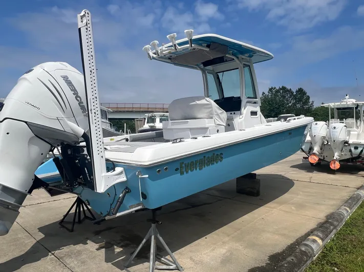  Yacht Photos Pics 2023 Everglades 253 CC boat with blue hull, parked on a concrete surface under a clear sky.