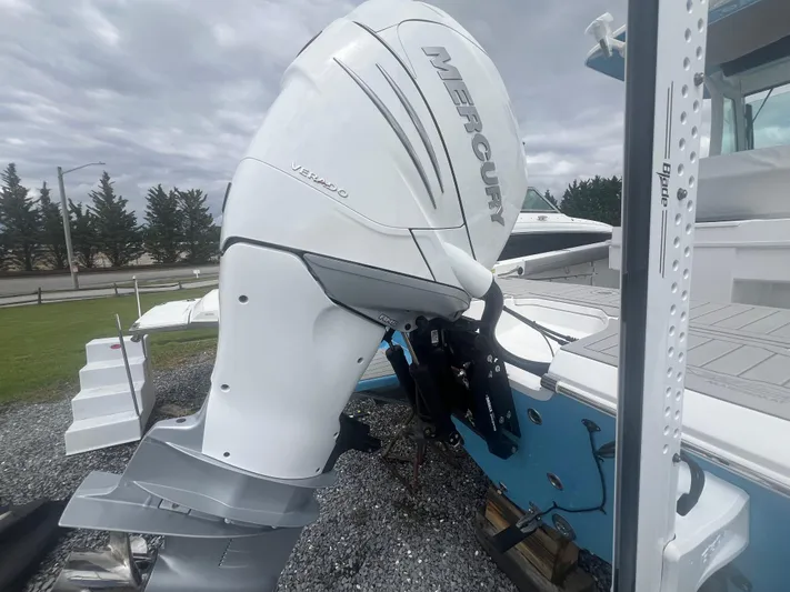  Yacht Photos Pics 2023 Everglades 253 CC boat with Mercury outboard motor, parked on gravel.