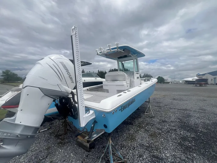  Yacht Photos Pics 2023 Everglades 253 CC boat with outboard motor on gravel lot under cloudy sky.