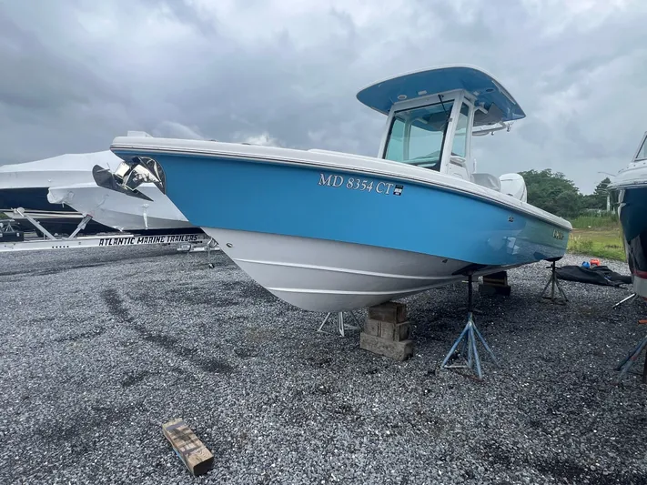  Yacht Photos Pics 2023 Everglades 253 CC boat on stands, blue hull, overcast sky.