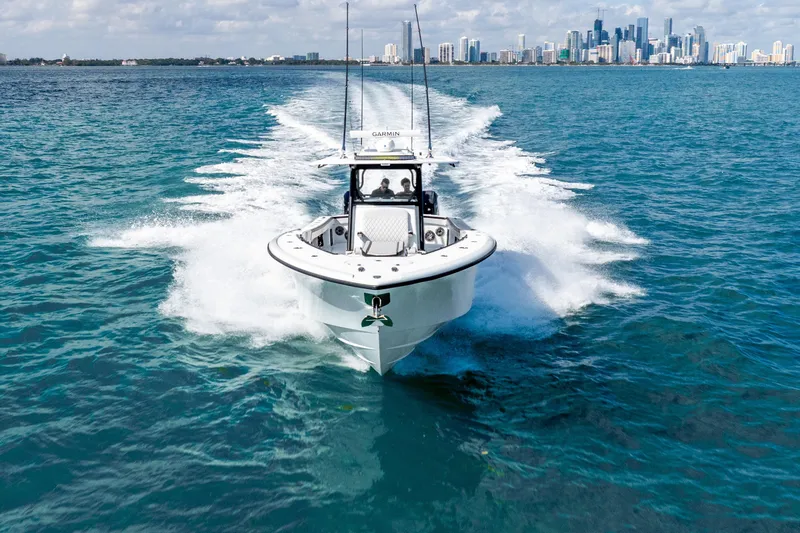  Yacht Photos Pics 2024 Yellowfin 39 Offshore boat cruising on blue ocean with city skyline in background.