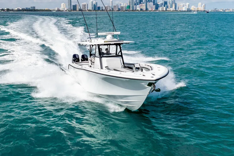  Yacht Photos Pics 2024 Yellowfin 39 Offshore boat cruising on blue ocean with city skyline in background.