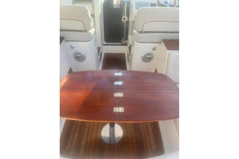 Andiamo Yacht Photos Pics Interior of 2006 Chris-Craft Corsair 33 with wooden table and seating.