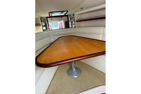 Andiamo Yacht Photos Pics 2006 Chris Craft Corsair Heritage interior with triangular wooden table and white seating.