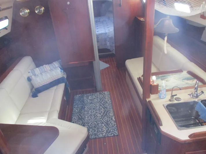  Yacht Photos Pics Interior of 1999 Island Packet 380 sailboat with cozy seating and wooden flooring.