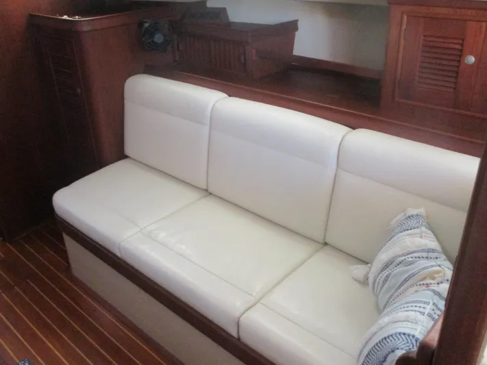  Yacht Photos Pics White leather sofa in 1999 Island Packet 380 yacht interior, with wooden cabinetry and striped pillow.