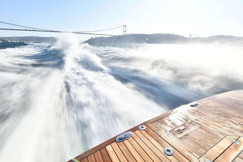 Falcon F-42 2x440 Hp Yanmar Yacht Photos Pics 2025 Falcon Yachts F-42 cruising swiftly, creating waves, with a bridge in the background.