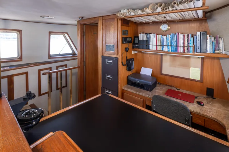  Yacht Photos Pics Cozy 1974 Willard 1201 boat interior with desk, bookshelves, and navigation equipment.