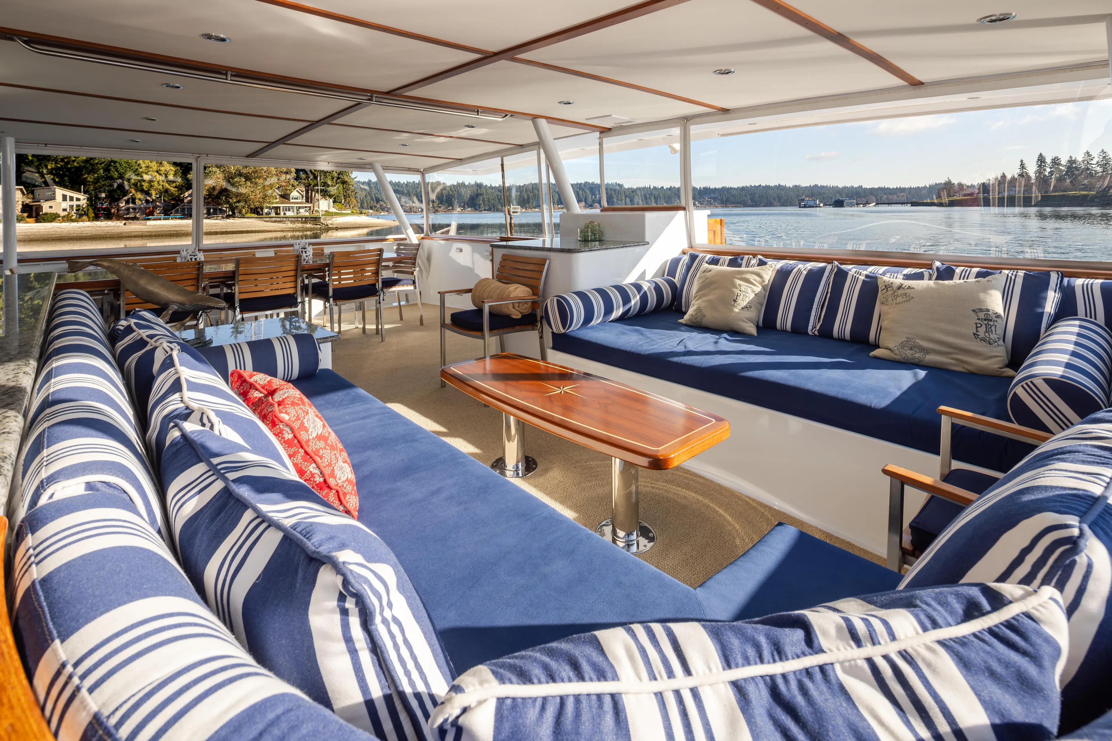  Yacht Photos Pics Luxurious 1974 Willard 1201 yacht interior with blue-striped seating and scenic waterfront view.