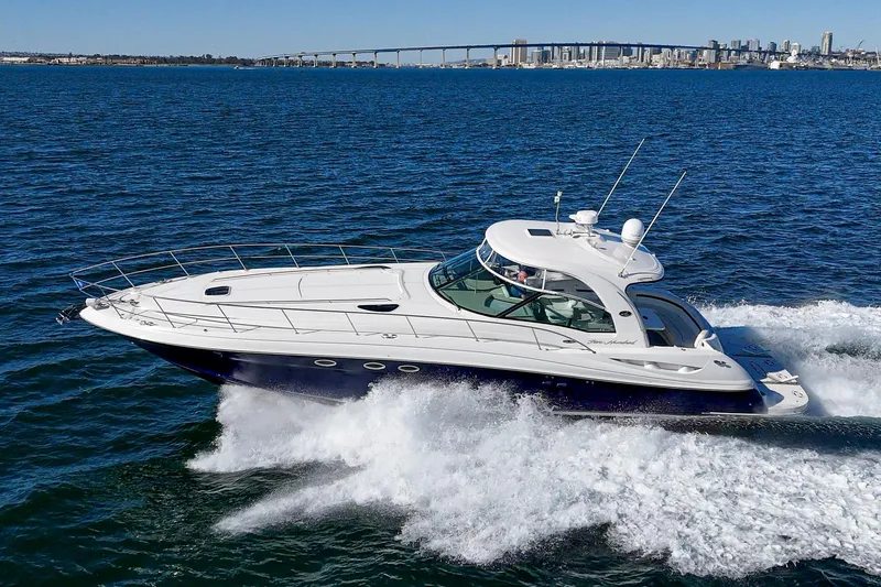 Enough 4 Now! Yacht Photos Pics 2005 Sea Ray 500 Sundancer yacht cruising on open water with city skyline in background.