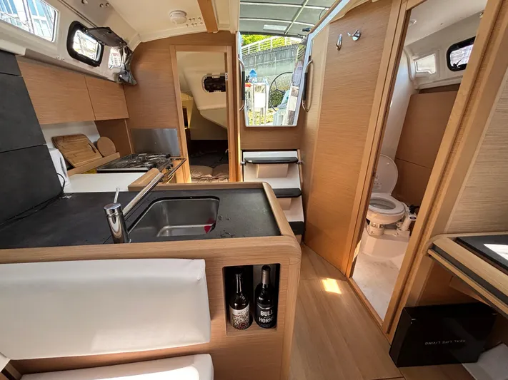  Yacht Photos Pics Interior of 2023 Jeanneau Sun Odyssey 349 sailboat, featuring modern kitchen and compact bathroom.