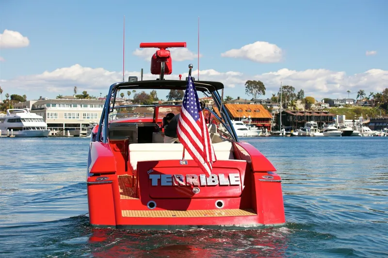  Yacht Photos Pics Red 2002 Hallett Express Cruiser with American flag on water.