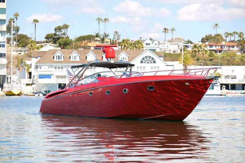  Yacht Photos Pics Red 2002 Hallett Express Cruiser boat on calm water near coastal homes.