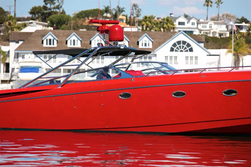  Yacht Photos Pics Red 2002 Hallett Express Cruiser boat on water, with houses in the background.