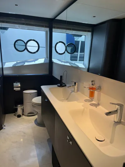  Yacht Photos Pics Modern yacht bathroom with dual sinks, circular windows, and sleek fixtures on a Princess X80, 2023.