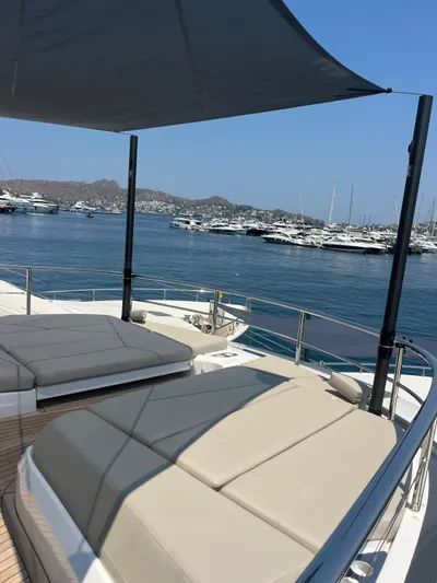  Yacht Photos Pics Luxurious 2023 Princess X80 yacht deck with sunbeds, overlooking a serene marina.