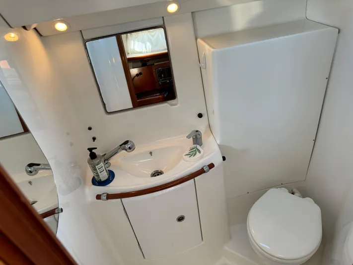 Interlude Yacht Photos Pics Compact bathroom in a 2002 Beneteau 393 yacht with sink, mirror, and toilet.