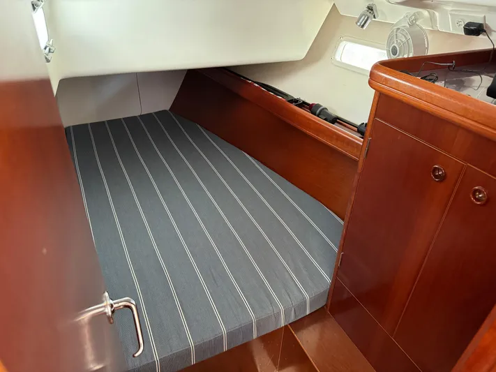 Interlude Yacht Photos Pics Cozy cabin interior of 2002 Beneteau 393 sailboat with striped bedding and wooden finish.
