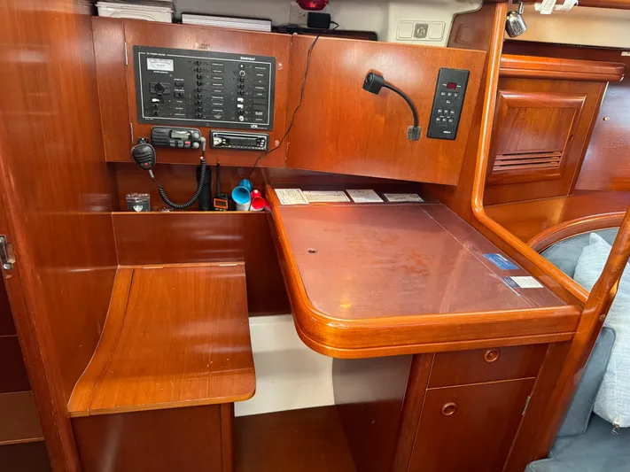 Interlude Yacht Photos Pics Navigation station of a 2002 Beneteau 393 sailboat with control panel and wooden desk.