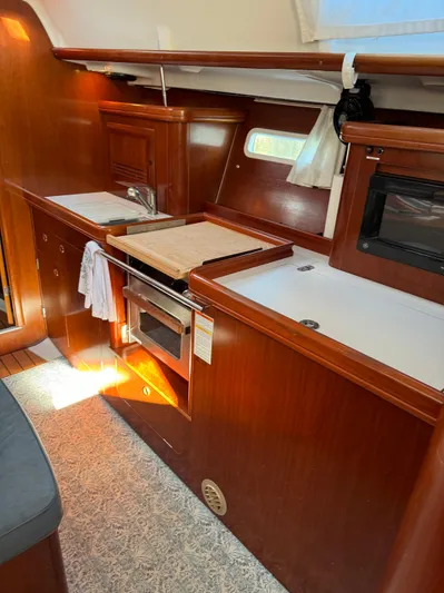Interlude Yacht Photos Pics Interior of 2002 Beneteau 393 yacht with wooden cabinetry and compact kitchen area.