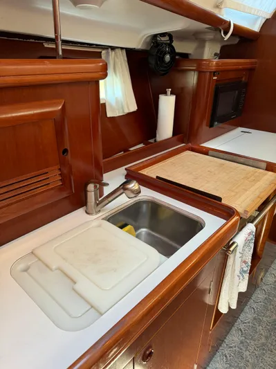 Interlude Yacht Photos Pics 2002 Beneteau 393 yacht kitchen with wooden cabinetry, sink, and countertop.
