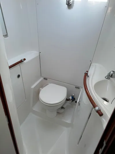 Interlude Yacht Photos Pics Beneteau 393 2002 yacht bathroom with toilet and sink, featuring sleek white design.