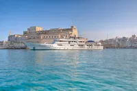 Luxury yacht "Displacement Twin Screw" (1982) docked near historic waterfront buildings.