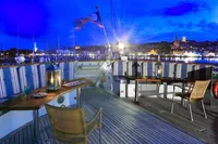 Luxurious yacht deck with seating, lanterns, and scenic harbor view at dusk, 1982 Custom Displacement Twin Screw.