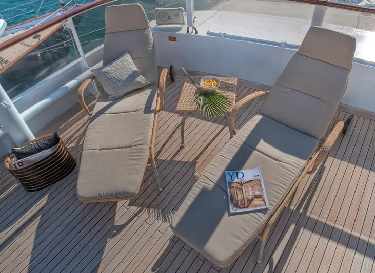 Sanssouci Star Yacht Photos Pics Two cushioned loungers on a yacht deck with a small table, magazine, and decorative items.