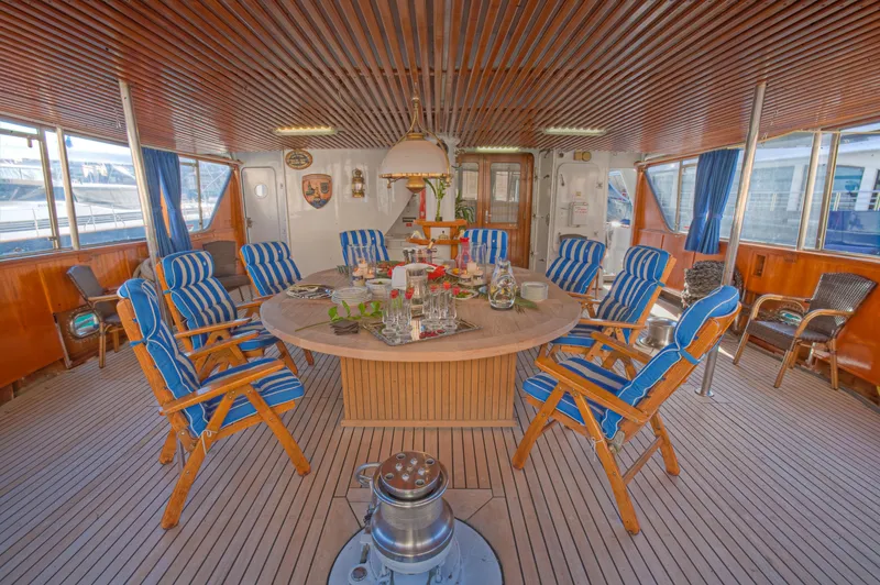 Sanssouci Star Yacht Photos Pics Luxurious yacht interior with striped chairs, round table, and wooden decor, 1982 Custom Displacement Twin Screw.