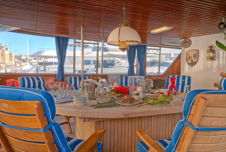 Sanssouci Star Yacht Photos Pics Luxurious yacht dining area with blue-striped chairs, elegant table setting, and marina view.