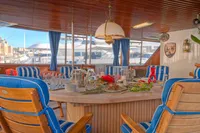 Luxurious yacht dining area with blue-striped chairs, elegant table setting, and marina view.