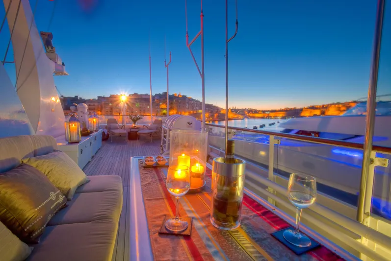 Sanssouci Star Yacht Photos Pics Luxurious yacht deck at sunset with candles, wine glasses, and cityscape view.