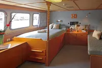 Luxurious cabin interior of 1982 Custom Displacement Twin Screw yacht with cozy bed and seating area.