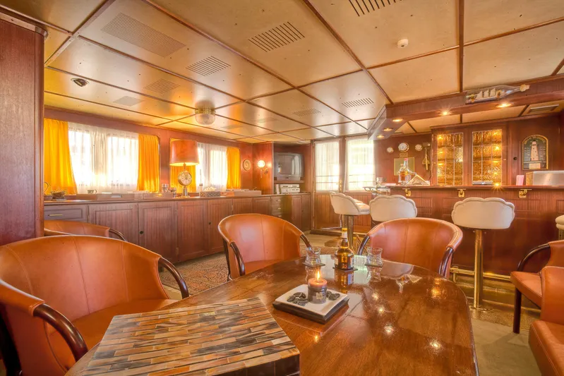 Sanssouci Star Yacht Photos Pics Luxurious yacht interior with wooden decor, leather chairs, and a well-stocked bar, 1982 Custom model.