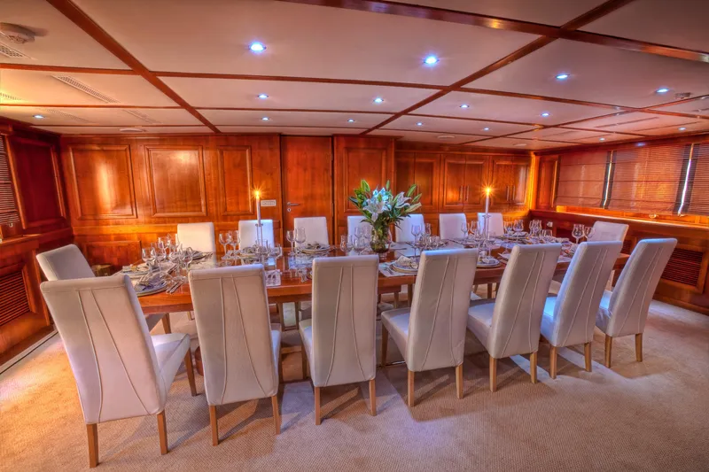 Sanssouci Star Yacht Photos Pics Luxurious yacht dining room with elegant table setting, white chairs, and wooden paneling, 1982 Custom Displacement Twin Screw.