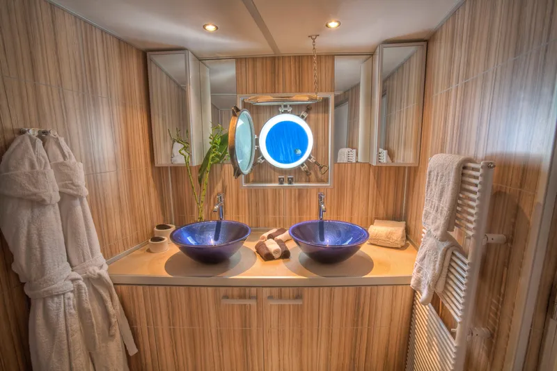 Sanssouci Star Yacht Photos Pics Luxurious bathroom with dual blue glass sinks, wooden paneling, and modern fixtures on a 1982 custom yacht.