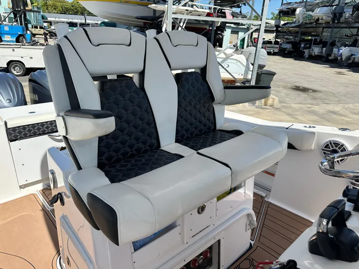 Yacht Photos Pics 2022 Tidewater 280 CC boat with dual cushioned seats and armrests in a marina setting.