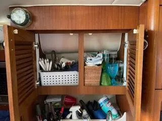 Pathological Yacht Photos Pics Wooden cabinet with open doors, showing organized storage inside a 2000 Pursuit 3400 Express boat.