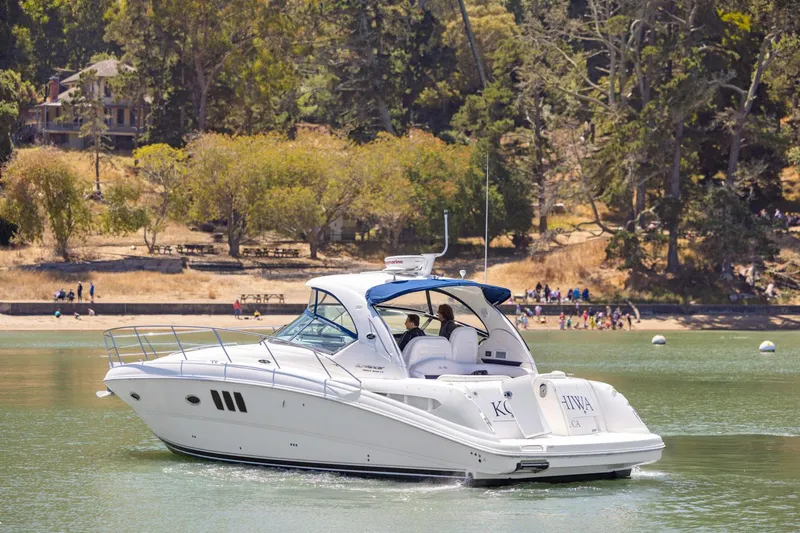 Konichiwa Yacht Photos Pics 2010 Sea Ray 390 Sundancer yacht cruising on a serene lake with a wooded shoreline.