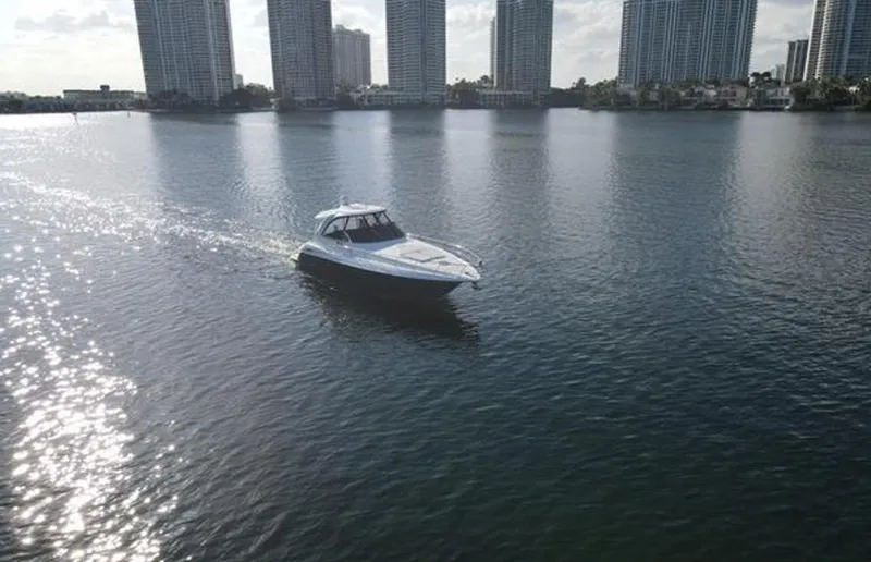  Yacht Photos Pics 2009 Cruisers Yachts 460 Express cruising on a sunlit waterway with city skyline backdrop.