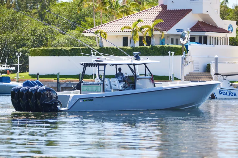  Yacht Photos Pics 2022 Contender 44 ST boat with multiple engines docked near a waterfront house.