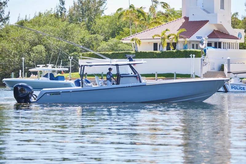  Yacht Photos Pics 2022 Contender 44 ST boat on calm water near a marina with lush greenery.