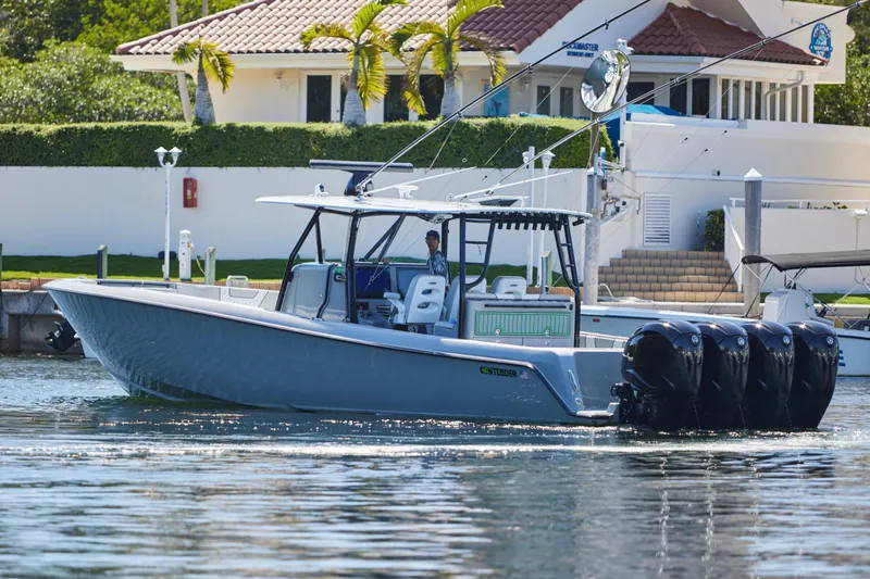  Yacht Photos Pics 2022 Contender 44 ST boat with four engines cruising near a waterfront home.