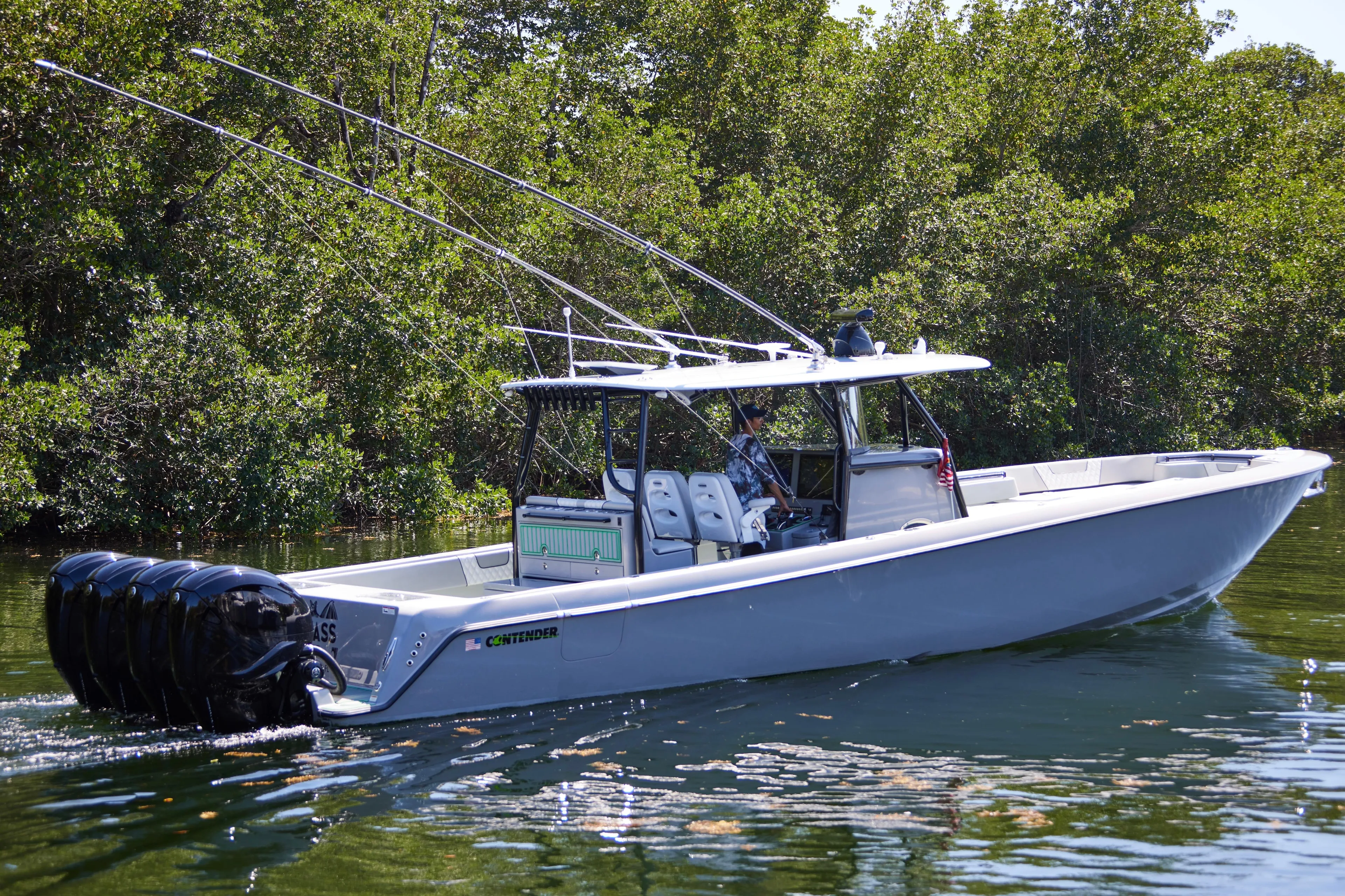  Yacht Photos Pics 2022 Contender 44 ST boat cruising on a calm waterway, surrounded by lush greenery.
