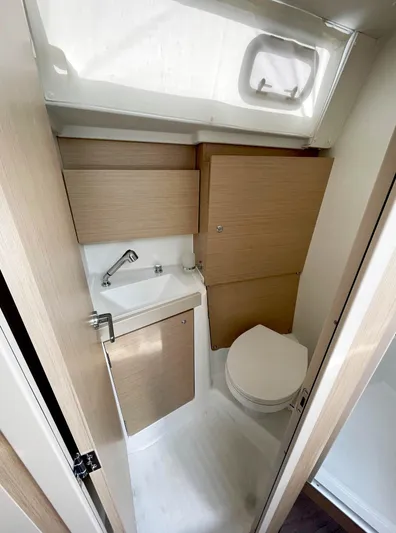 Odyssey Yacht Photos Pics Compact bathroom in 2022 Beneteau Oceanis 38.1 yacht with modern fixtures and wood accents.