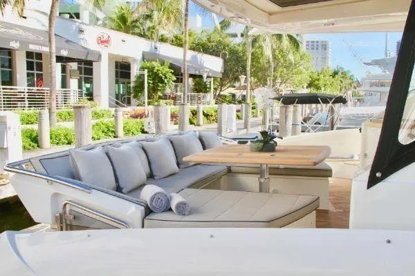  Yacht Photos Pics Luxurious 2012 Absolute 70 yacht with elegant outdoor seating and table, docked near a waterfront building.