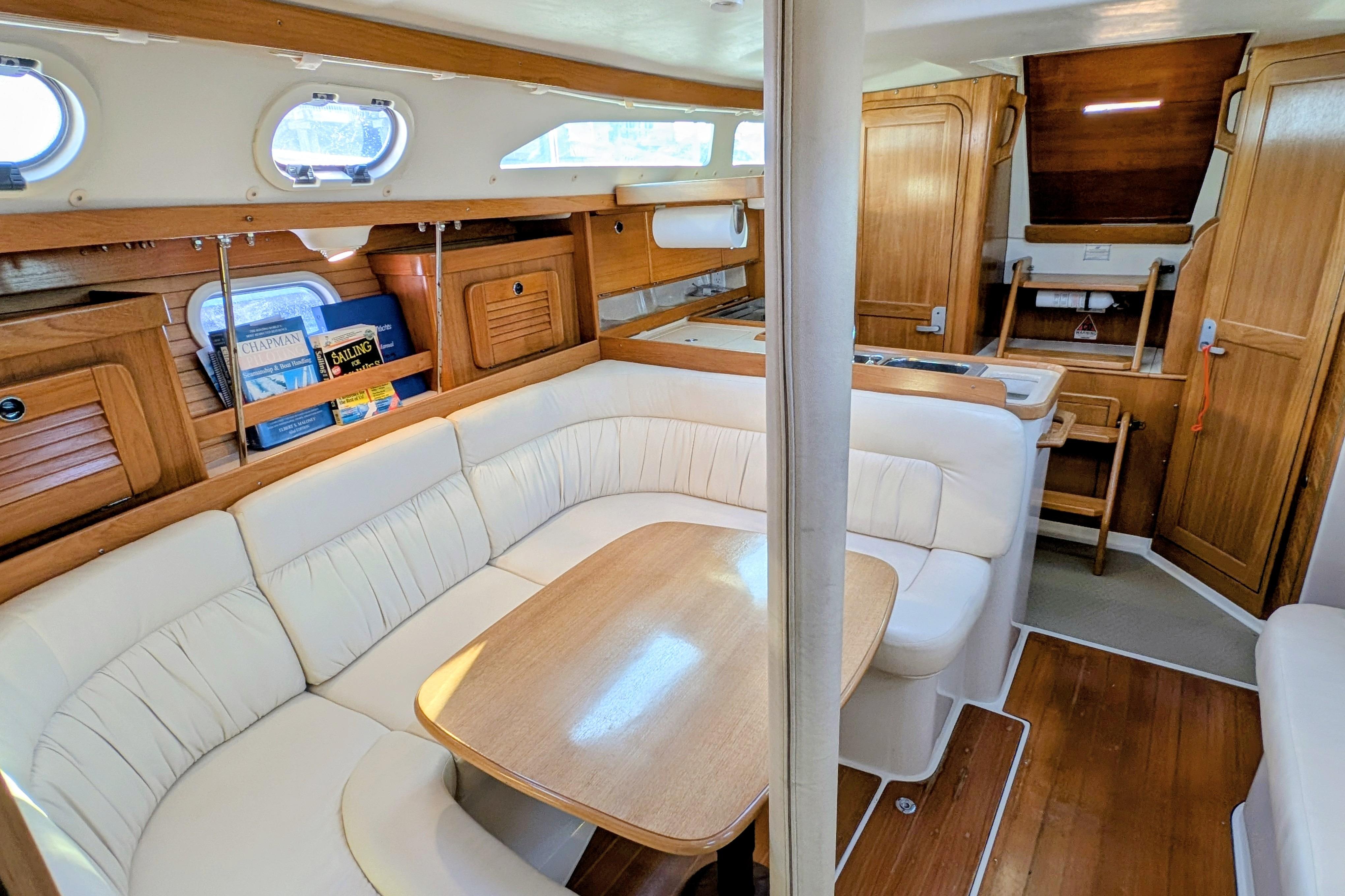 Interior of 2003 Catalina 34 MkII sailboat with cozy seating and wooden cabinetry.