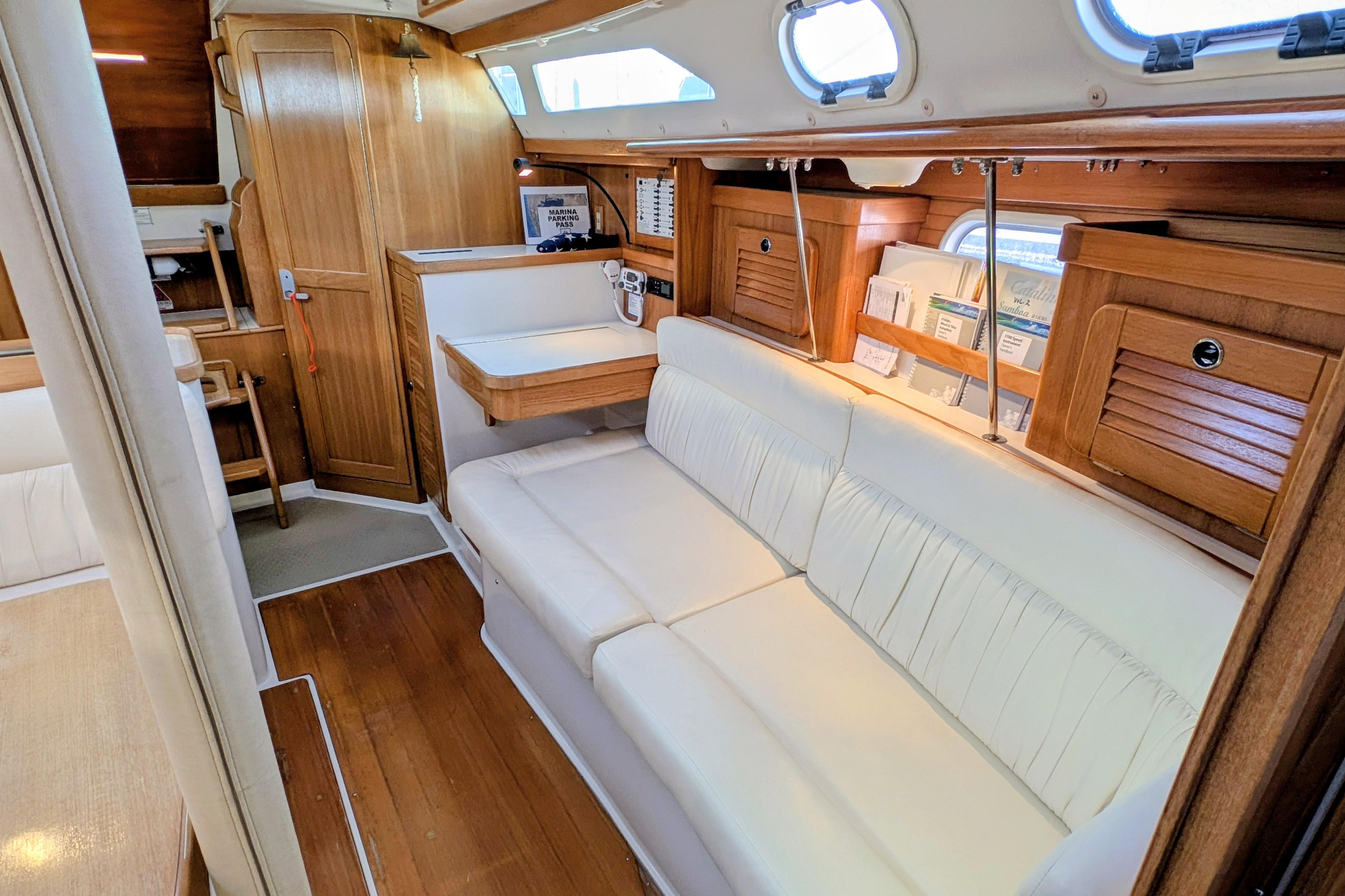 Interior of 2003 Catalina 34 MkII sailboat with white seating and wooden cabinetry.